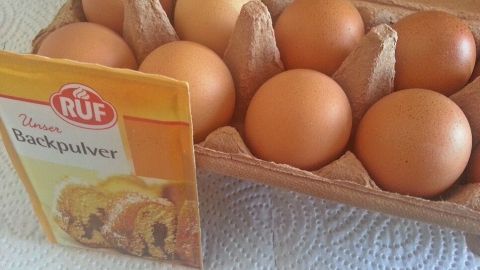 Ein Karton mit Eiern liegt auf einer weißen Tischdecke, daneben eine Backmischung von RUF für einen einfachen Kochprozess.
