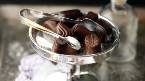 Ein eleganter Glasbehälter steht auf einem Tisch, gefüllt mit Low Carb Pralinen und dekoriert mit einem Löffel.
