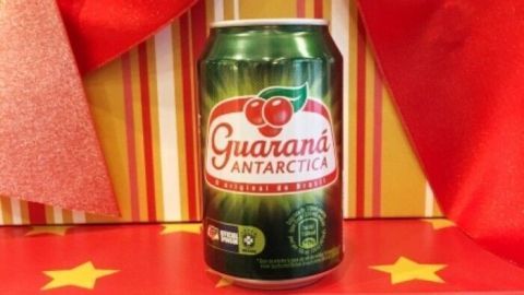 Eine grüne Dose Guaraná Limonade steht auf einer roten Geschenkbox, umgeben von festlicher Dekoration.