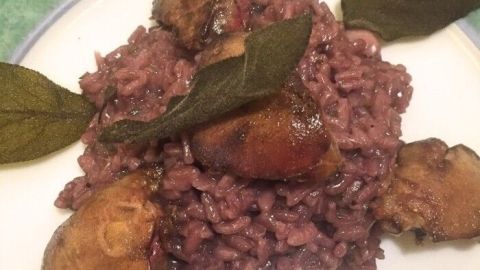 Rotweinrisotto liegt präsent auf einem Teller, garniert mit Leberstücken und frischen Salbeiblättern, appetitlich angerichtet.