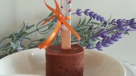 Eine Trinkschokolade mit Gewürzen steht auf einem weißen Teller, dekoriert mit Lavendel und einem gespaltenen Holzstab.