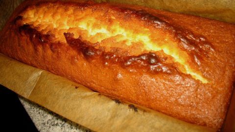 Ein saftiger Zitronenkuchen liegt in einer Backform, frisch gebacken, mit einer goldbraunen, knusprigen Kruste.