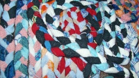 Bunte, geflochtene Teppichstreifen liegen spiralförmig aufeinander und bilden einen Fleckerlteppich aus verschiedenen Stoffen.