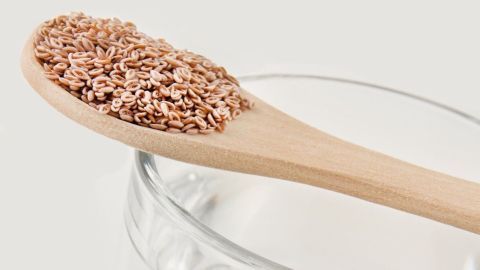Vorübergehendes Sodbrennen ist oft harmlos - aber sehr lästig. Ein natürliches Hausmittel hilft. Ein Holzlöffel mit Flohsamenschalen liegt auf einem Glas mit klarem Wasser, das zur Linderung von Sodbrennen dient.