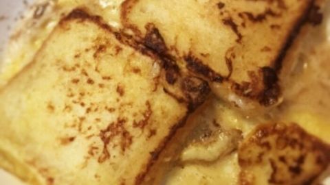 Drei goldbraun gebratene French Toast-Scheiben liegen in einer weißen Schüssel, umgeben von leicht süßem Ahornsirup.