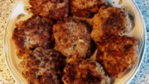 Saftige Frikadellen liegen appetitlich auf einem Teller und sind bereit zum Servieren, umgeben von einer hellen Tischoberfläche.