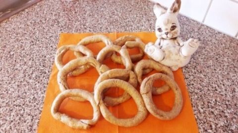 Die Fastenbeugerl liegen auf einem orangefarbenen Tuch, während eine porzellanene Figur daneben sitzt.