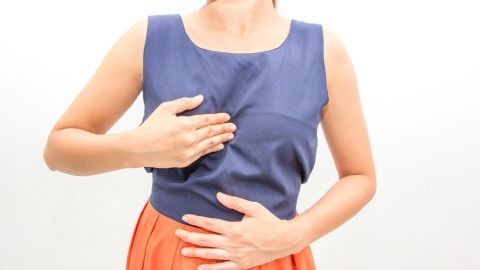 Eine Person hält sich die Brust und den Bauch, möglicherweise als Zeichen von Unwohlsein oder Beschwerden.