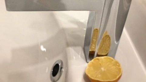 Eine moderne Wasserarmatur steht neben ausgepressten Zitronen in einem Waschbecken, in einem Badezimmer-Szenario.