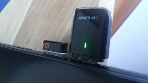 Ein WLAN-Adapter leuchtet grün, während er mit einem Laptop verbunden ist, um 5-GHz-Signale zu empfangen.