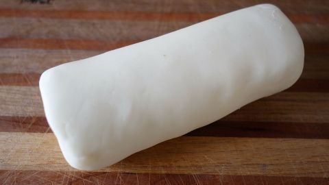 Eine weiße Modelliermasse liegt auf einem Holzbrett, bereit zum Formen und Gestalten in kreativen Projekten.