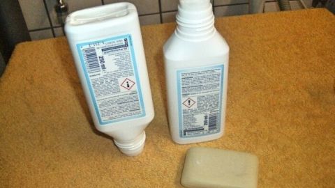 Eine Flasche Gallseife steht neben einem Stück Gallseife auf einem handtuchartigen Untergrund im Badezimmer.