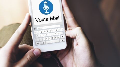 Ein Smartphone wird gehalten, während der Benutzer mit der Mailbox spricht. Der Bildschirm zeigt "Voice Mail" an.
