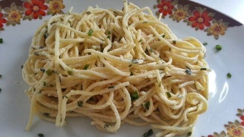 Ein Spaghettisalat liegt auf einem blumengeschmückten Teller, leicht angerichtet und bereit zum Servieren.