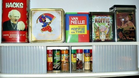Ein umgebautes CD-Regal dient als Gewürzschrank und zeigt dekorative Dosen mit verschiedenen Kräutern und Gewürzen.