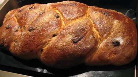 Ein goldbrauner Hefe-Osterzopf liegt auf einem Backblech, frisch gebacken und duftend, bereit zum Servieren.