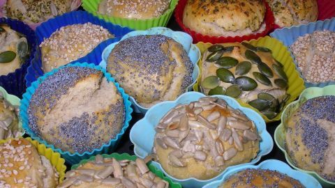 Bunte Muffinformen mit frischen Brötchen aus Backpulver-Hefe-Teig stehen auf einem Tisch, bereit zum Servieren.