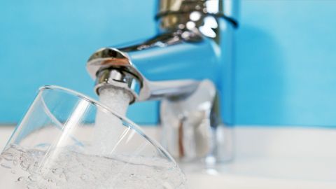 Ein Wasserhahn gießt frisches Wasser in ein Glas. Das Bild verdeutlicht mögliche Gesundheitsrisiken durch Blei im Trinkwasser.