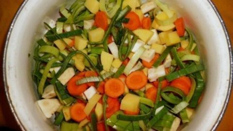Bunte Gemüsesuppe für Singles und Kochanfänger wird in einer weißen Schüssel mit frischem, gehacktem Gemüse zubereitet.