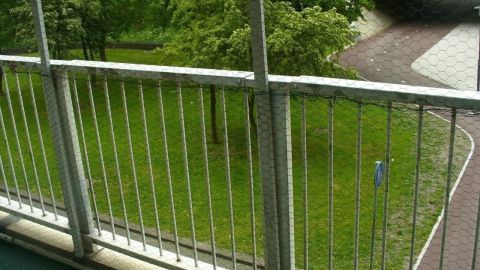 Ein Balkon mit Sicherheitsnetz wurde vorbereitet, um sicherzustellen, dass Katzen nicht entkommen, während er grüne Bäume umgibt.