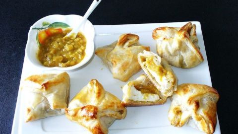 Blätterteignester gefüllt mit Ziegenkäse liegen zusammen mit einem scharfen Relish auf einem weißen Teller.