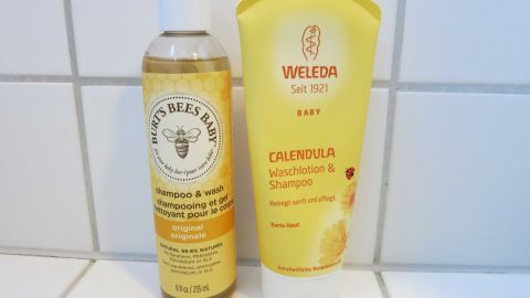 Milde Shampoos wie z. B: Shampoos für Babys helfen bei Problemen mit Schuppen sehr gut. Außerdem ist es auch noch viel preiswerter als andere spezielle Produkte. Zwei Flaschen Haarpflegeprodukte stehen auf einer hellen Fliesenoberfläche, die für die Behandlung von Schuppen gedacht sind.