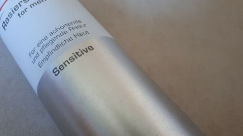 Eine silberne Rasierschaumdose liegt auf einem hellen Untergrund, bereit zum Entleeren, mit der Aufschrift "Sensitive".