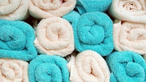 Gestapelte, flauschige Frotteehandtücher in sanften Blau- und Beigetönen liegen ordentlich aufeinander.