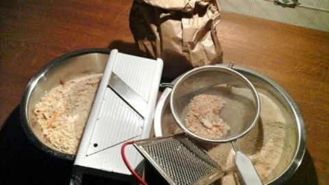 Eine Mischung aus alten Semmeln und Küchengeräten liegt auf einem Holztisch, bereit zum Verwerten und Zubereiten.