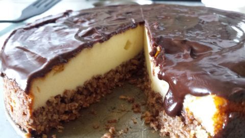 Eine appetitliche New York Cheesecake mit Schokolade und Müsli ist angeschnitten und präsentiert sich auf einem Teller.