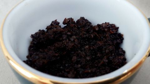 Ein Schüsselchen mit Kaffeesatz steht auf einem Tisch, bereit für ein Kokosöl Peeling, um die Haut zu pflegen.