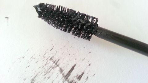 Ein Wimpernbürstchen steht auf einem weißen Untergrund, mit Schwarz von der Wimperntusche, um schöne Wimpern zu erzielen.