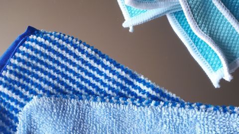 Blaue Reinigungstücher liegen übereinander, bereit, Spiegel ohne Chemie zu reinigen, auf einer glatten Oberfläche.