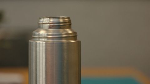 Eine Edelstahl-Thermoskanne steht auf einem Tisch, bereit zum Reinigen mit Geschirrspülpulver.