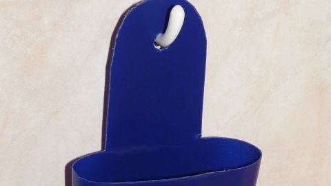 Ein blauer Halter für Shampoo-Flaschen hängt an einer Wandfliese im Badezimmer und bietet Stauraum für Pflegeprodukte.