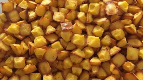 Kleine, goldbraun geröstete Würfel aus Kartoffeln liegen auf einem Teller, bereit als leckere Snacks für Hunde und Katzen.