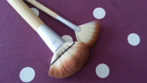 Zwei Pinsel liegen auf einem lila gepunkteten Untergrund, bereit für das Vergrößern des Pinselvolumens beim Makeup.
