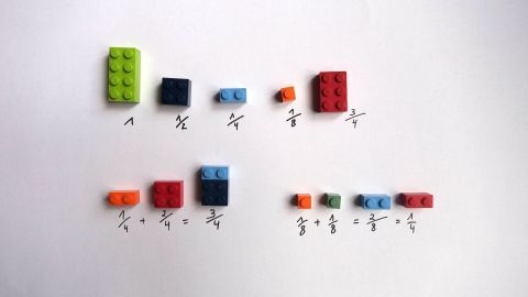 Bunte Lego-Steine sind geordnet, um Brüche darzustellen und zu lernen, auf einer weißen Fläche angeordnet.
