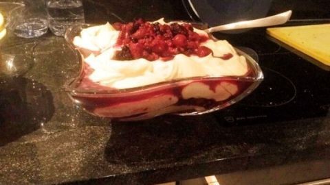 Ein leckeres Heidelbeerdessert mit weißer Schokolade, angerichtet in einer Schale, steht auf einer dunklen Küchenarbeitsplatte.