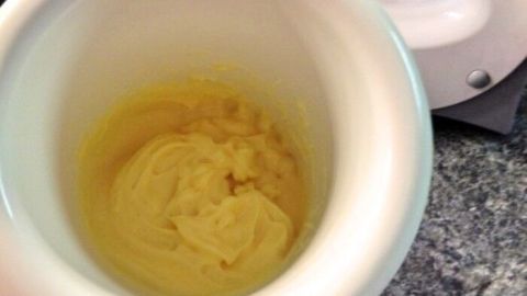 Gelbe, cremige Mayonnaise wird in einer weißen Schüssel zubereitet, während ein Handmixer daneben bereitliegt.