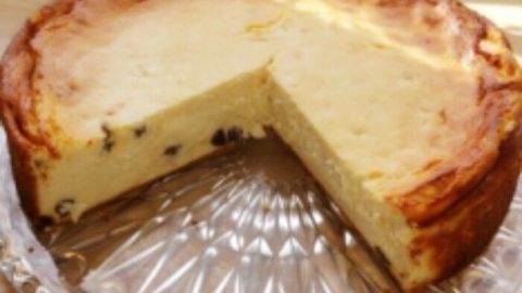Ein Käsekuchen ohne Boden wird auf einem gläsernen Teller präsentiert. Ein Stück fehlt, was ihn appetitlich macht.