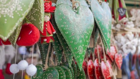 Bunte Herzchen hängen an einer Schnur. Sie sind mit Muster verziert und zeigen eine festliche Stimmung auf dem Markt.