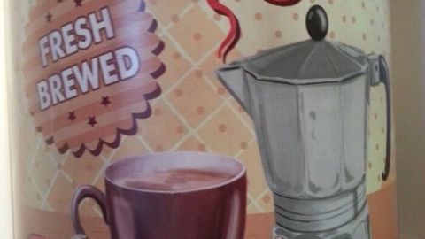 Eine Kaffeetasse mit frisch gebrühtem Kaffee steht neben einer traditionellen italienischen Kaffee-Pfanne in einem modernen Küchendesign.