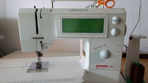 Eine Nähmaschine steht auf einem Tisch, während der Faden nach unten herausgezogen wird, um mit dem Nähen zu beginnen.