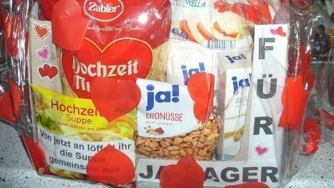 Ein liebevoll dekorierter Geschenkkorb mit roten Herzen und Snacks, um das Hochzeitsmotiv "Für Ja-Sager" zu feiern.