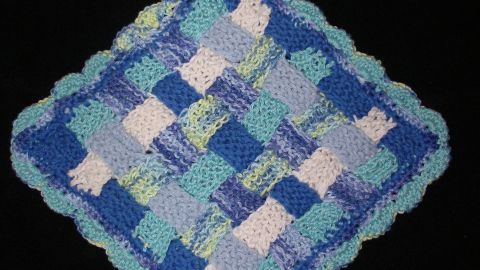Ein bunter Patchwork-Topflappen aus Garnresten hängt schützend in der Küche, bereit, heiße Töpfe zu greifen.