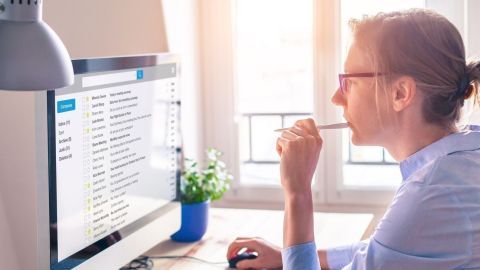 Ein Mann sitzt vor einem Computer und untersucht E-Mails, während er nach betrügerischen Mails über PayPal sucht.