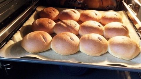 Quarkbrötchen backen im Ofen, gut gebräunt auf einem Blech, umgeben von der warmen, rauchigen Atmosphäre des Backvorgangs.