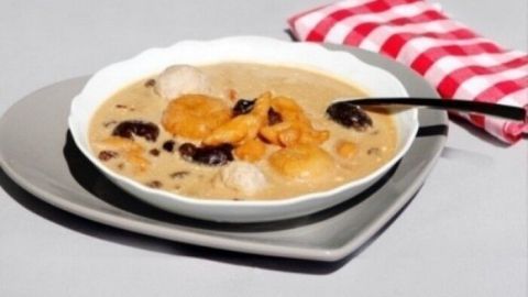 Eine Schale Schnitzsuppe aus Trockenfrüchten steht auf einem grauen Teller, umgeben von einem gestreiften Serviette.