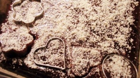 Quittenbrot mit Cranberries und Barberries liegt auf einem Blech, dekoriert mit Puderzucker und ausgestochenen Formen.